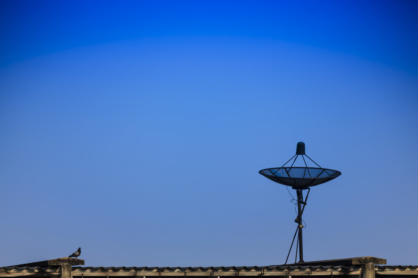Black satellite dish on the roof of the blue sky
