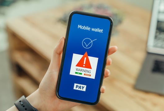 Canva-woman-hands-using-smartphone-and-login-mobile-banking-online-with-show-a-warning-screen-of-malware-dangers.